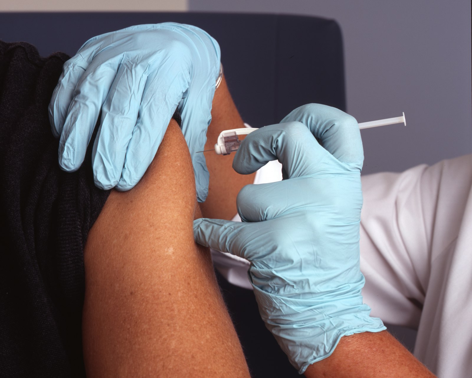 Vaccination dans le haut du bras par un professionnel ganté